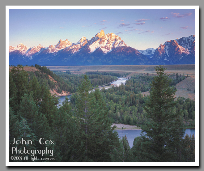 The freshly dusted Grand Teton glows in the light of the rising soon as the Snake River meanders along its way in the foreground.