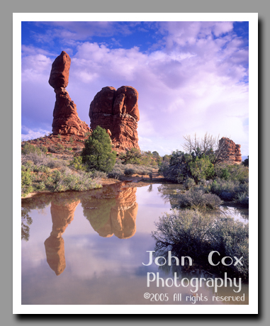 Balanced Rock reflects brilliantly in a pool left by recent rain showers in Arches National Park, Utah.
